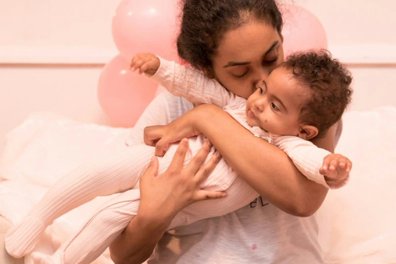 a  hugs her mother as she holds a pink baby