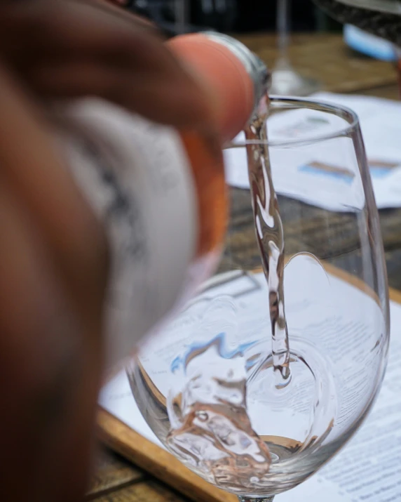 an image of someone pouring water into a wine glass