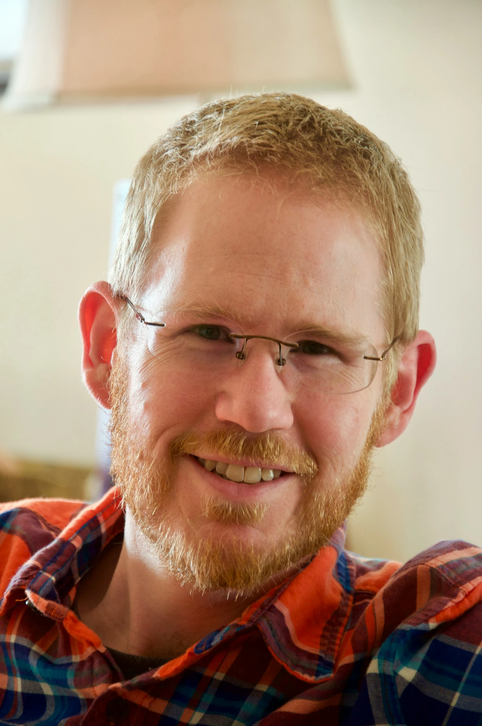 the man with glasses smiles next to a white object