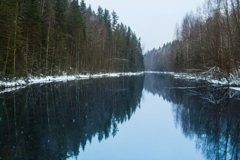 a river surrounded by trees and snow