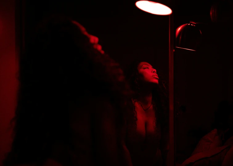 a woman standing under a red light near a lamp