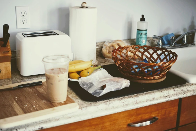 a wooden bowl filled with bananas next to a glass