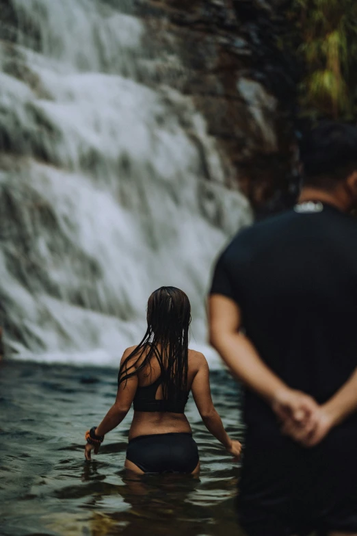 woman standing in water next to a waterfall