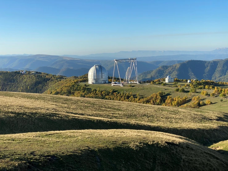 a large satellite dish in the background, surrounded by mountains