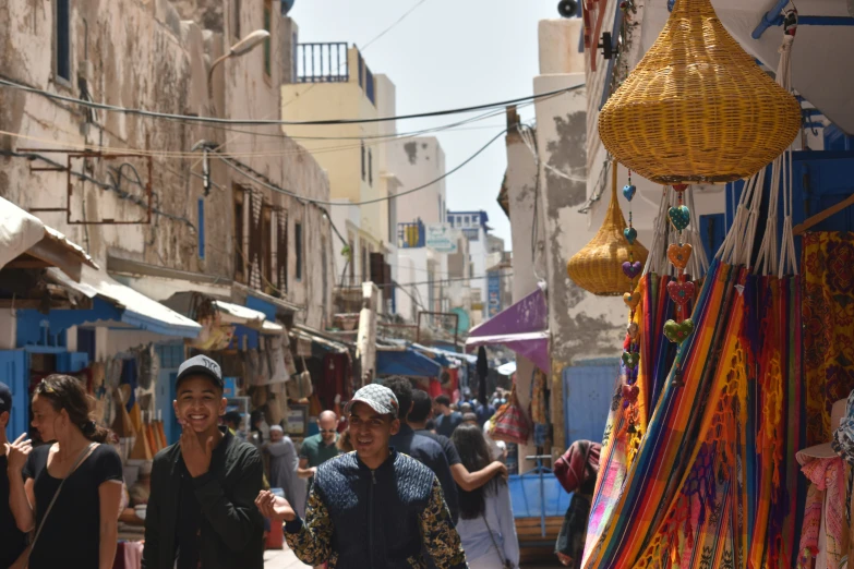 people strolling through an outdoor market, with other goods hanging in front of them