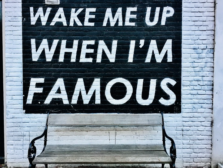 a bench next to a building under a sign that reads wake me up