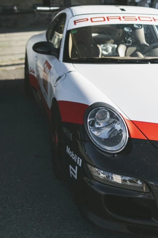 a white and red porsche sports car is parked near the sidewalk