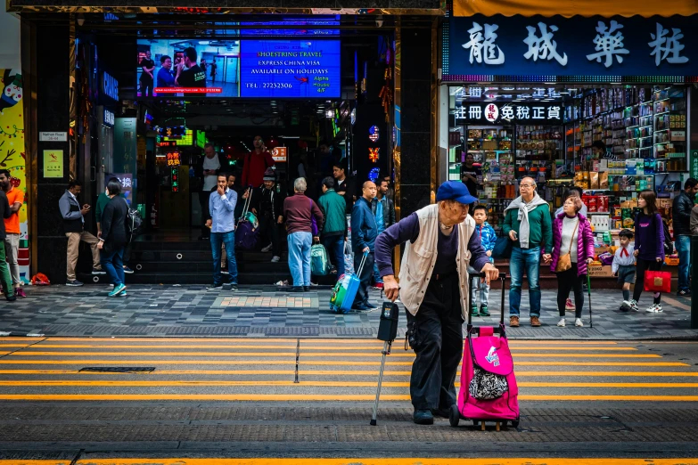 a man carrying two pink luggage bags across the street