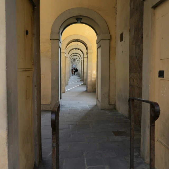 an alley in a building with columns and some light on