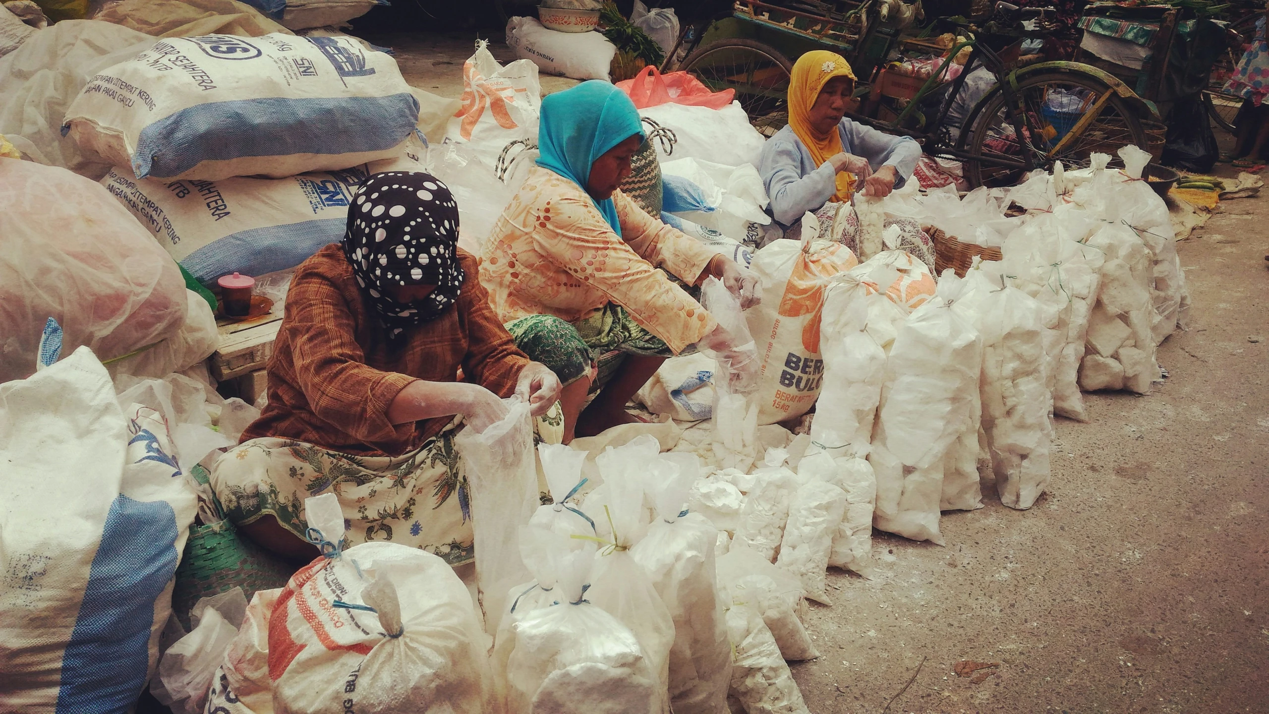 several women with bags standing at a road side