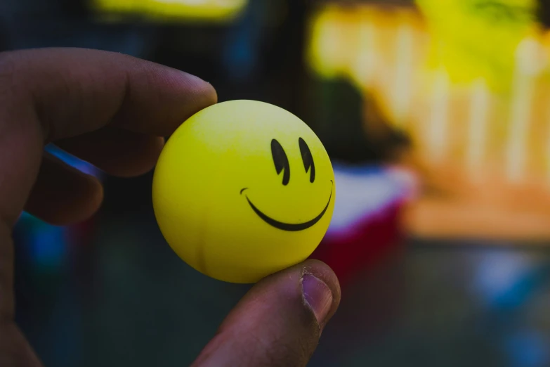 someone holding a small smiley face ball in their hand