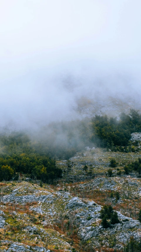 a picture of an open field with mist in the sky