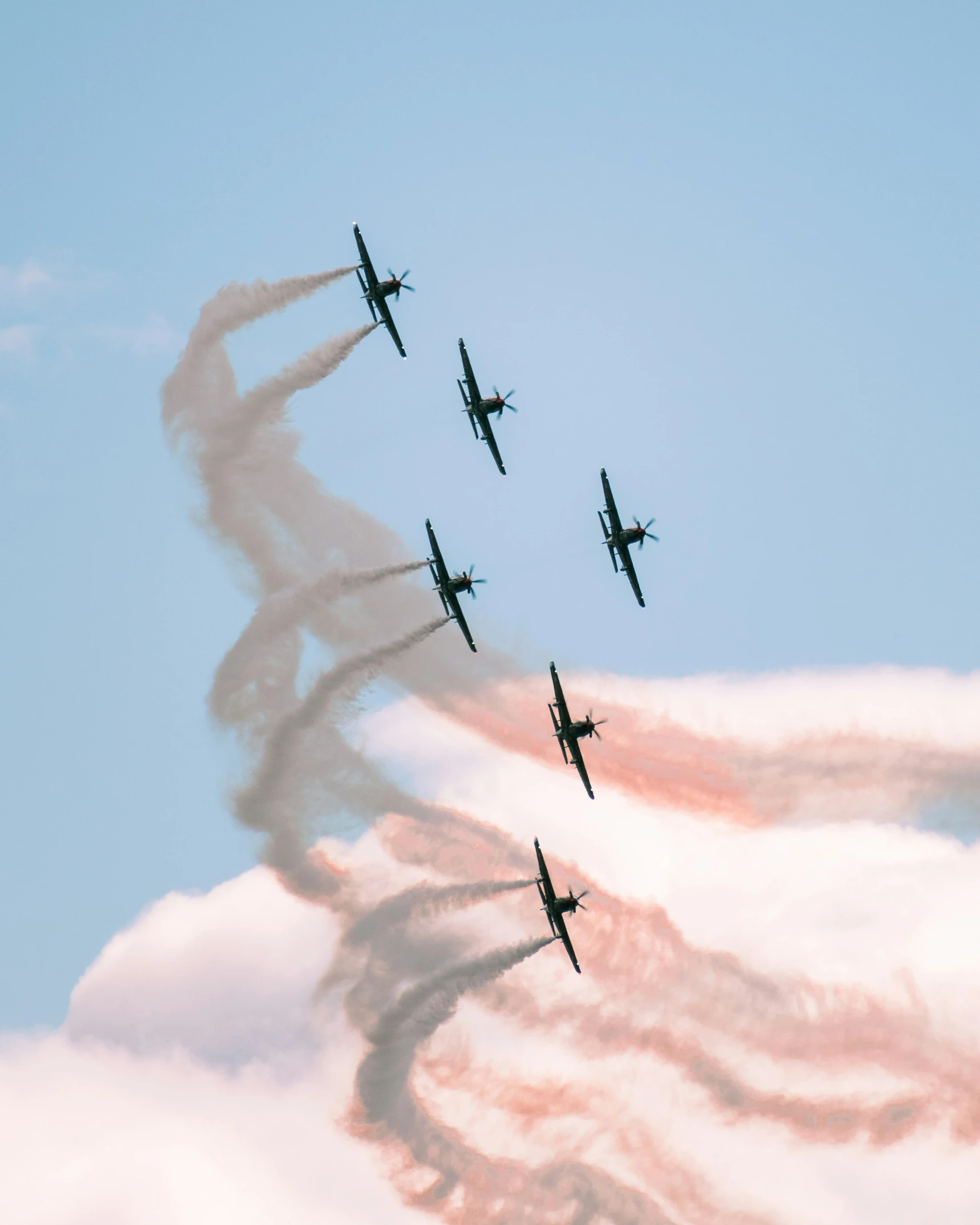 four planes flying through a cloudy blue sky