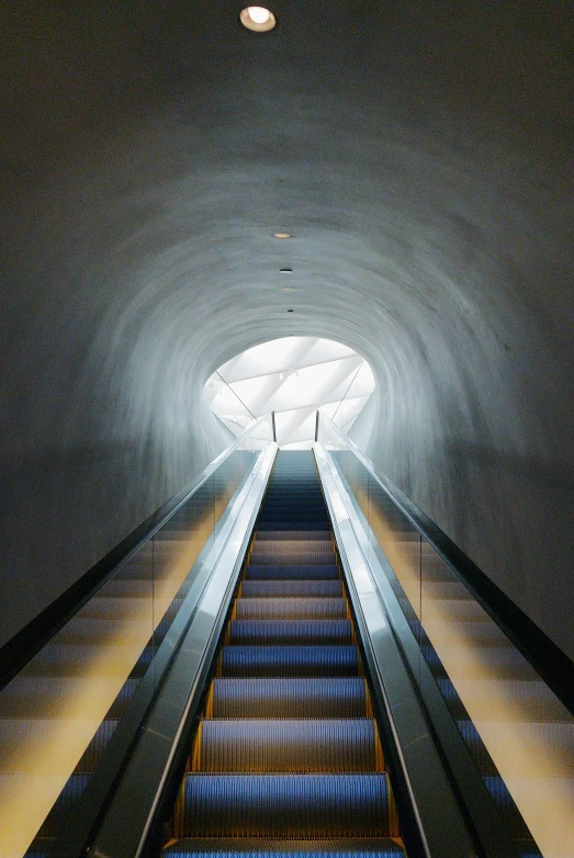 an escalator with a light at the end in a tunnel