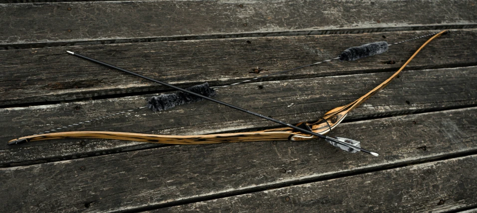 an arrow and bow rest on a wooden surface