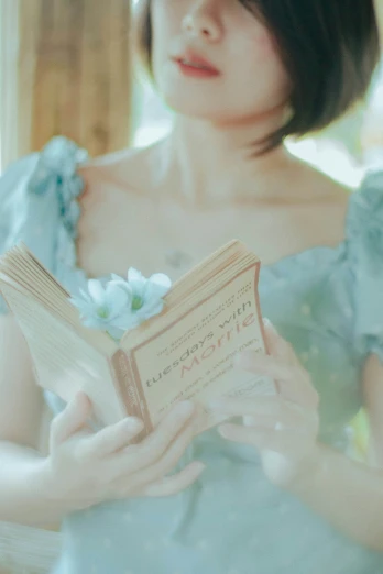 woman in blue dress holding open book with her hands