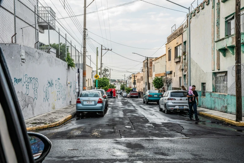 some cars parked on the side of a street and people crossing the road