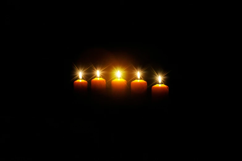 five candles that are burning brightly in the dark
