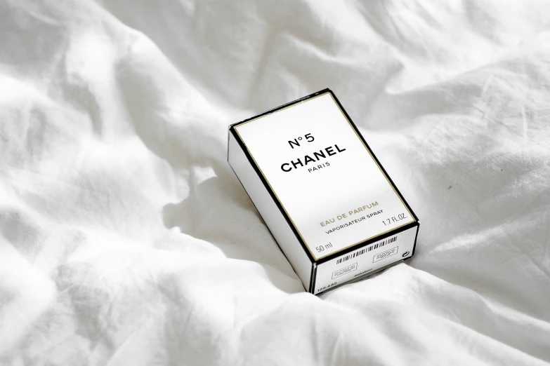 a package of perfume sitting on top of a bed