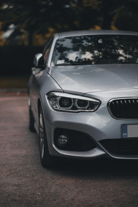 a gray bmw car is parked on the side of the road