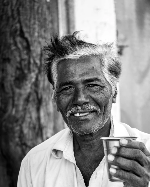 a man is smiling with a coffee cup in hand