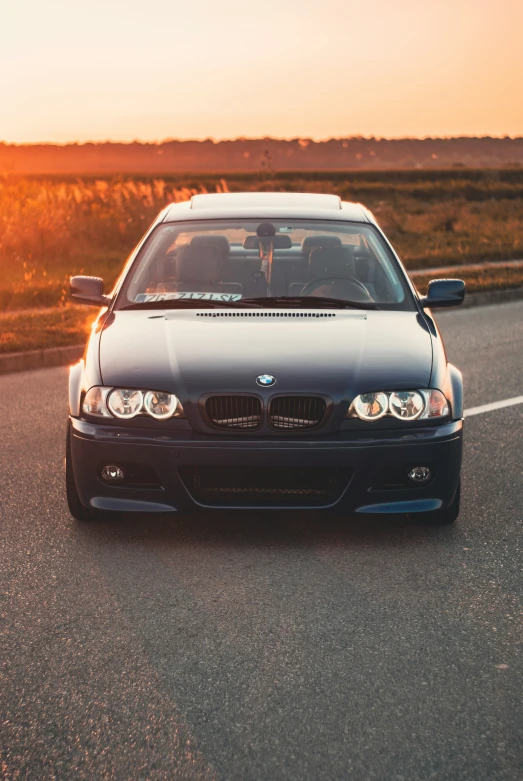 a black car drives down the highway, during a sunset