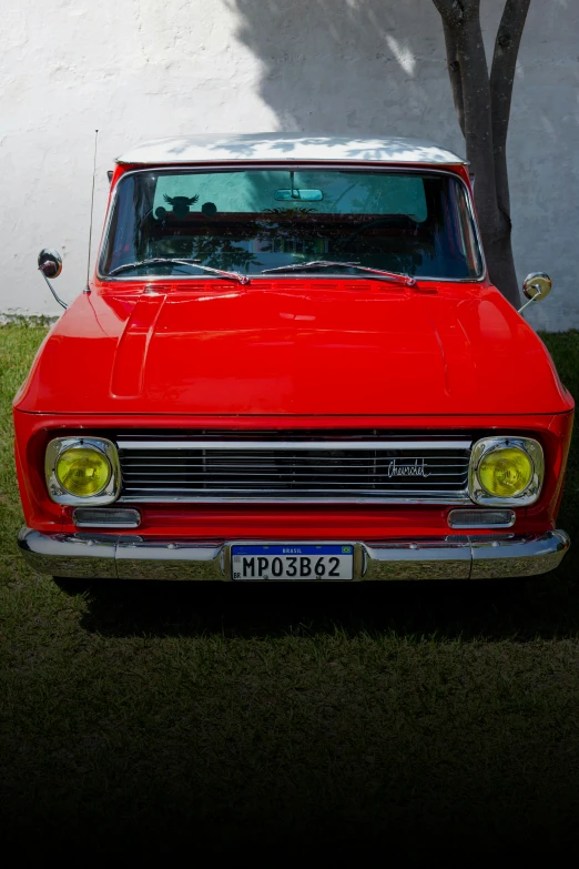 an older car parked on grass next to a building