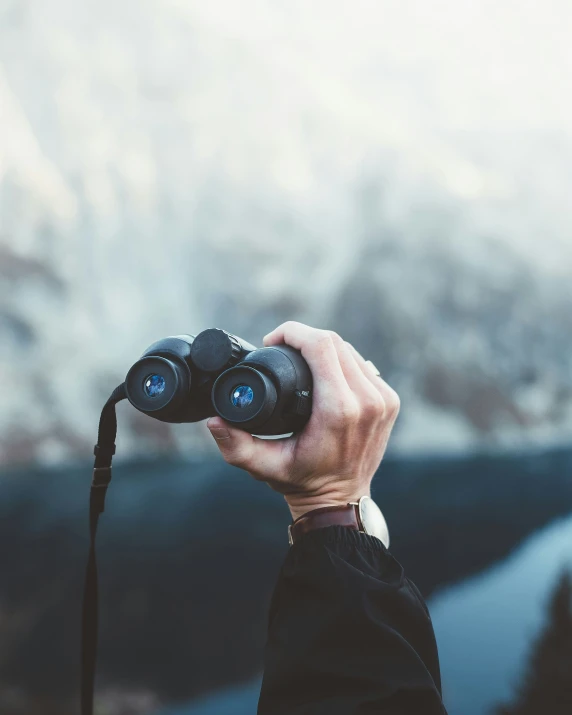 someone holding two binoculars in the air