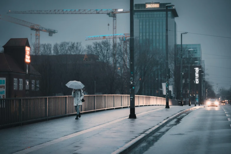 a woman walking down a city street in the rain with an umbrella