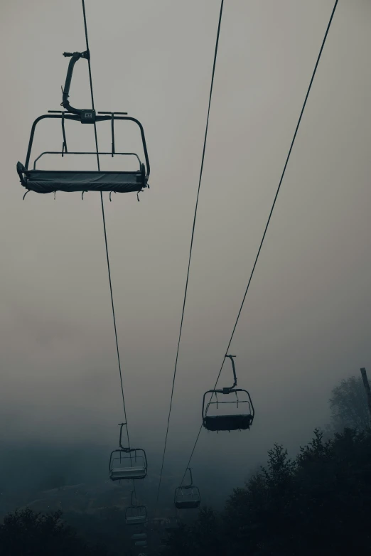 the ski lift is high up in the foggy sky