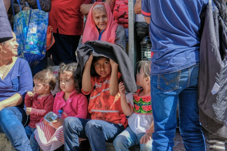 small children sitting on the side of a bench in front of an older lady