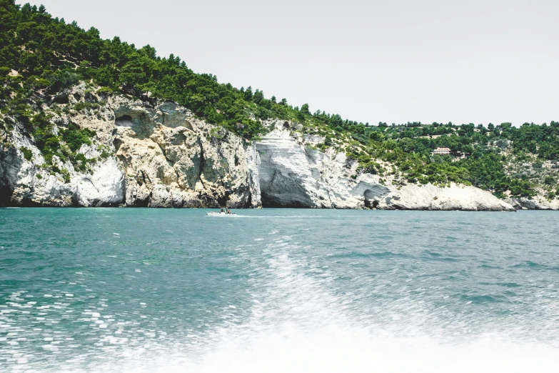 a boat floats next to an island with trees on top