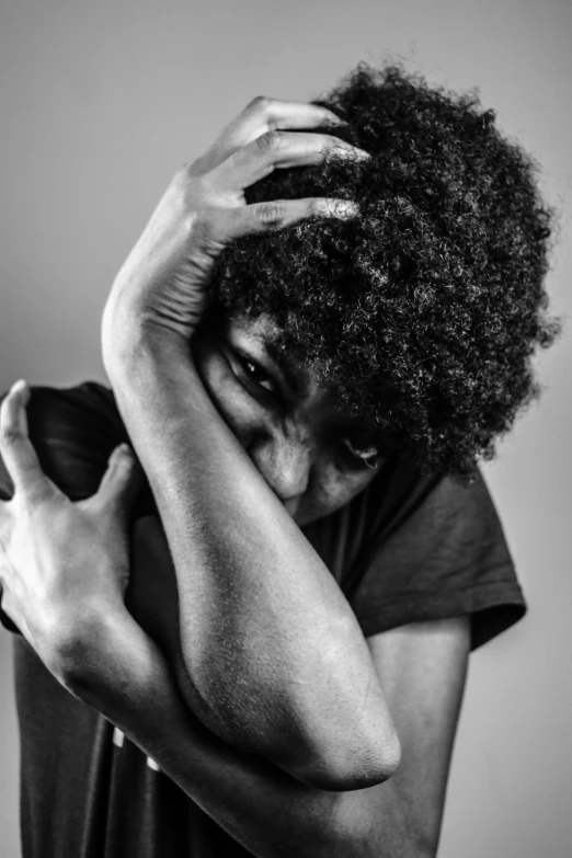 woman with natural curly hair covering her face