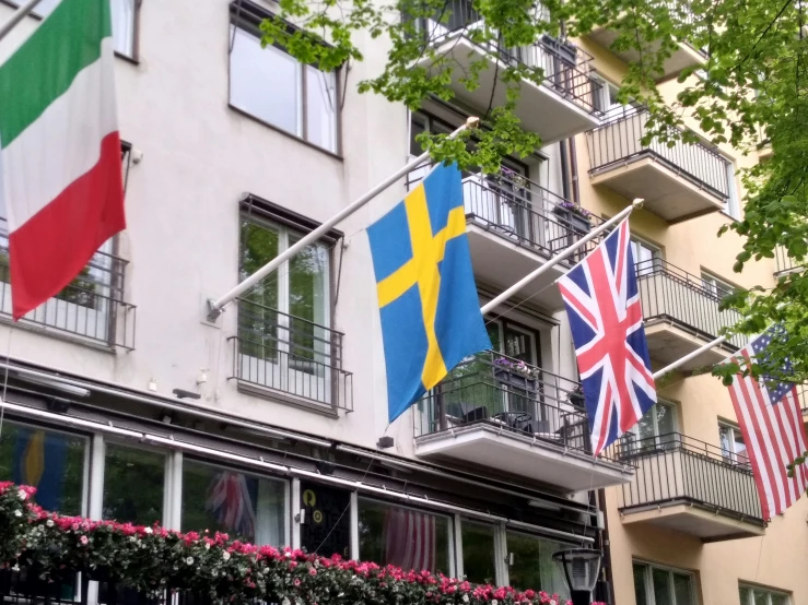 european and british flags hang from the balconys of a multi - story apartment building