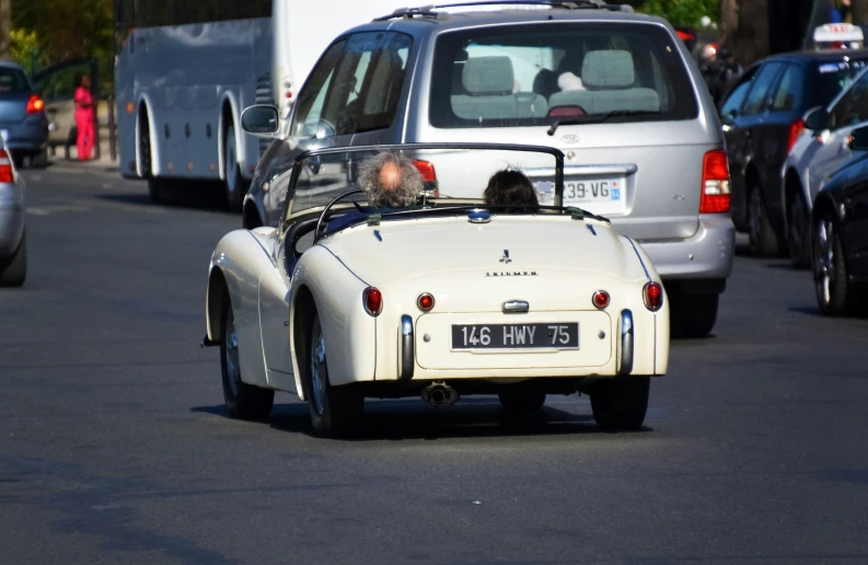 a man driving an old style car down the street