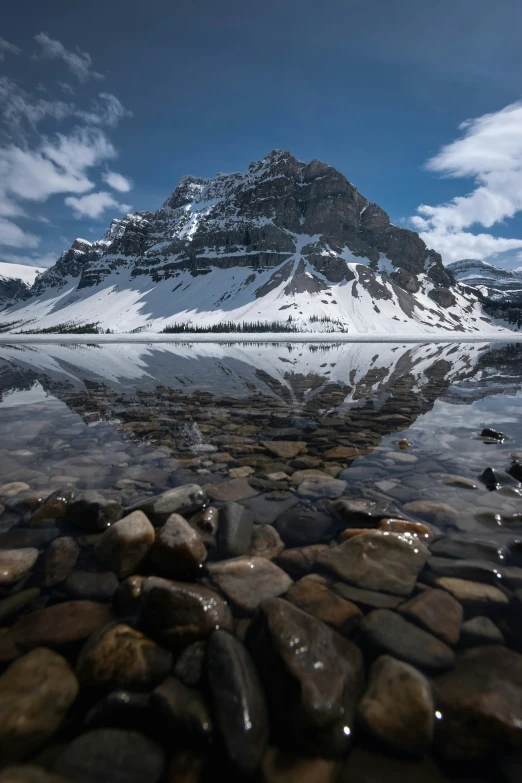 a mountain with snowy capped peaks is reflected in a pond