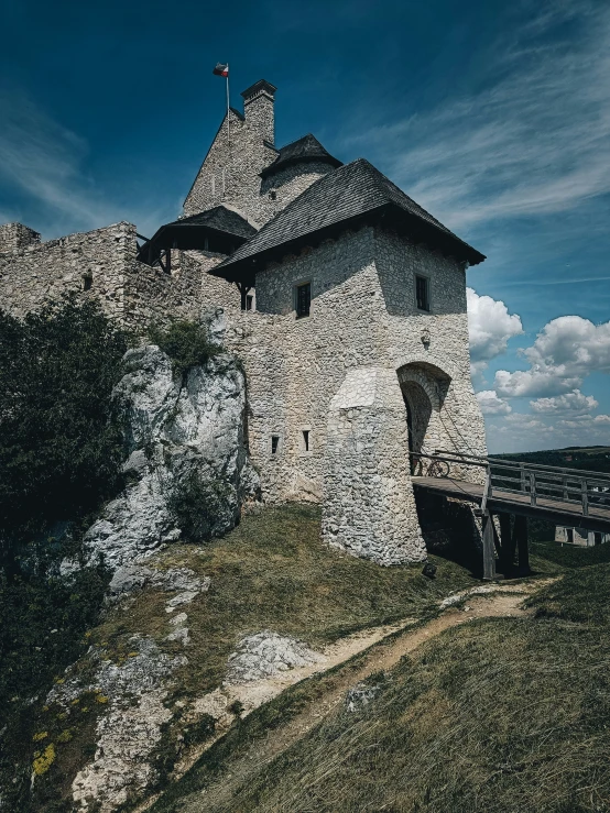 an old, stone house with a flag on top sits on top of the hill