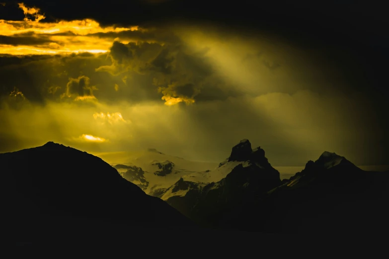 sunlight shining through clouds above a mountain range