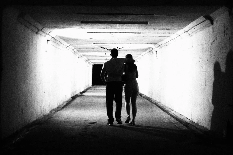 two people standing inside of a dark tunnel