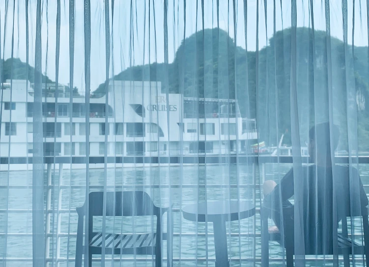 a person stands by an open window at a lake