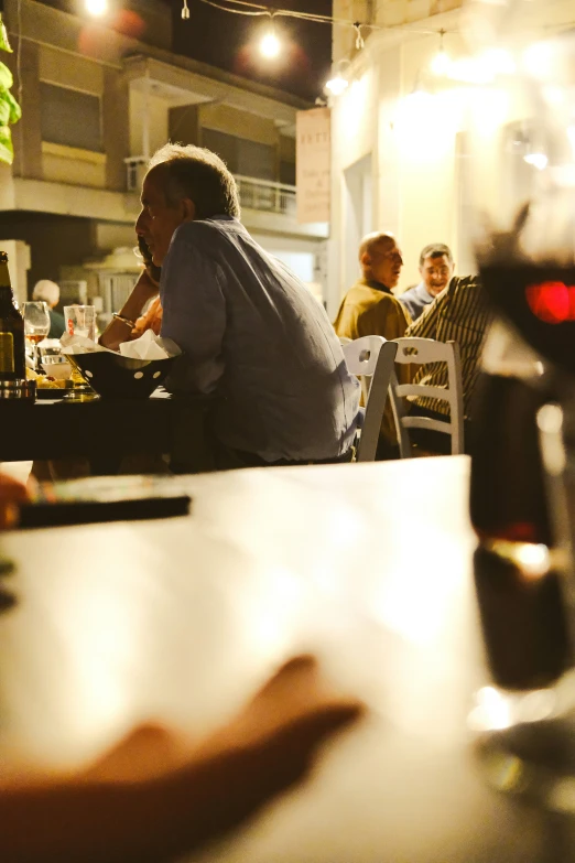 some people eating at a restaurant table next to a bottle of wine