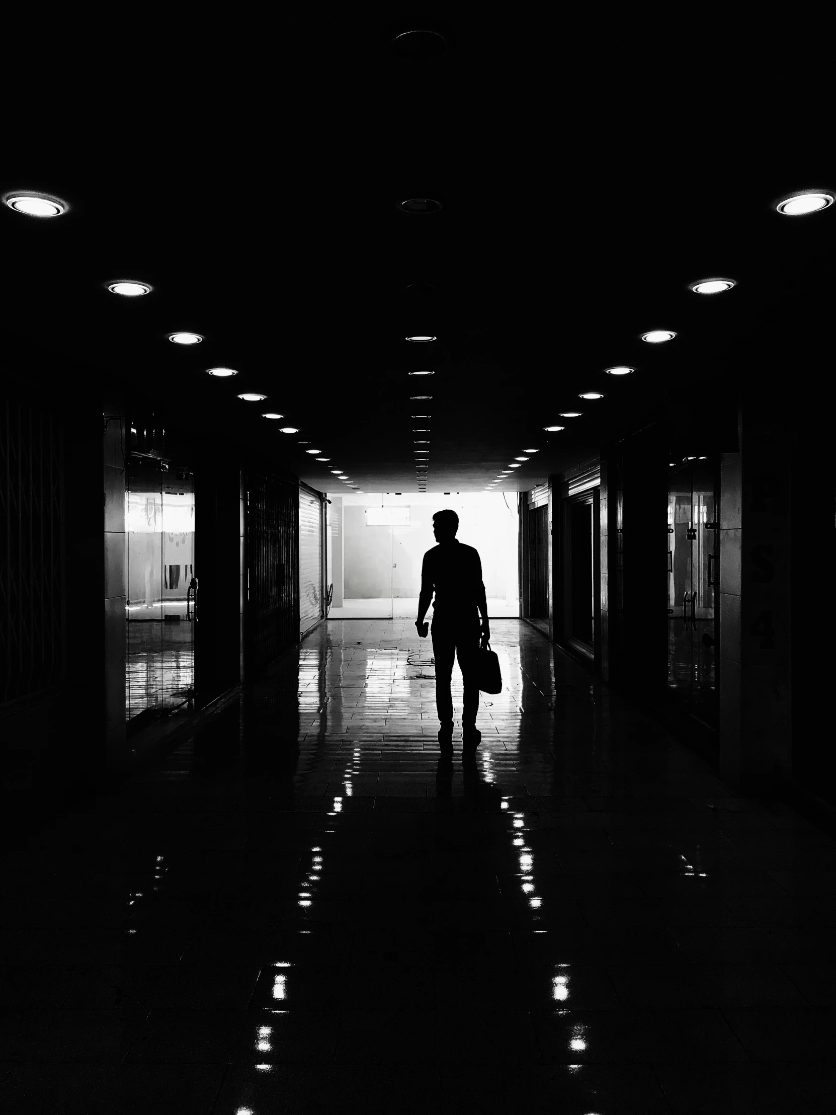 man with suitcase walking down hallway in building
