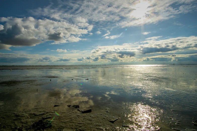 the sun is shining over an ocean with a blue sky and clouds