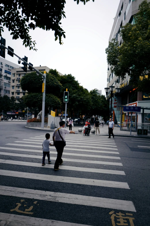 a man is holding the hand of a  while crossing a street