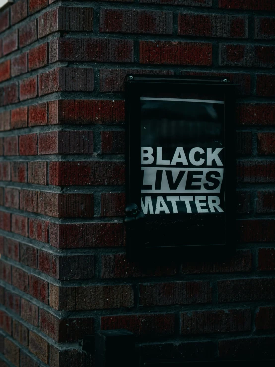 a black lives matter sign is displayed on a brick wall