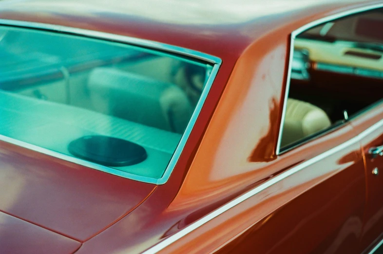 the front end of an old red car with its sunroof up