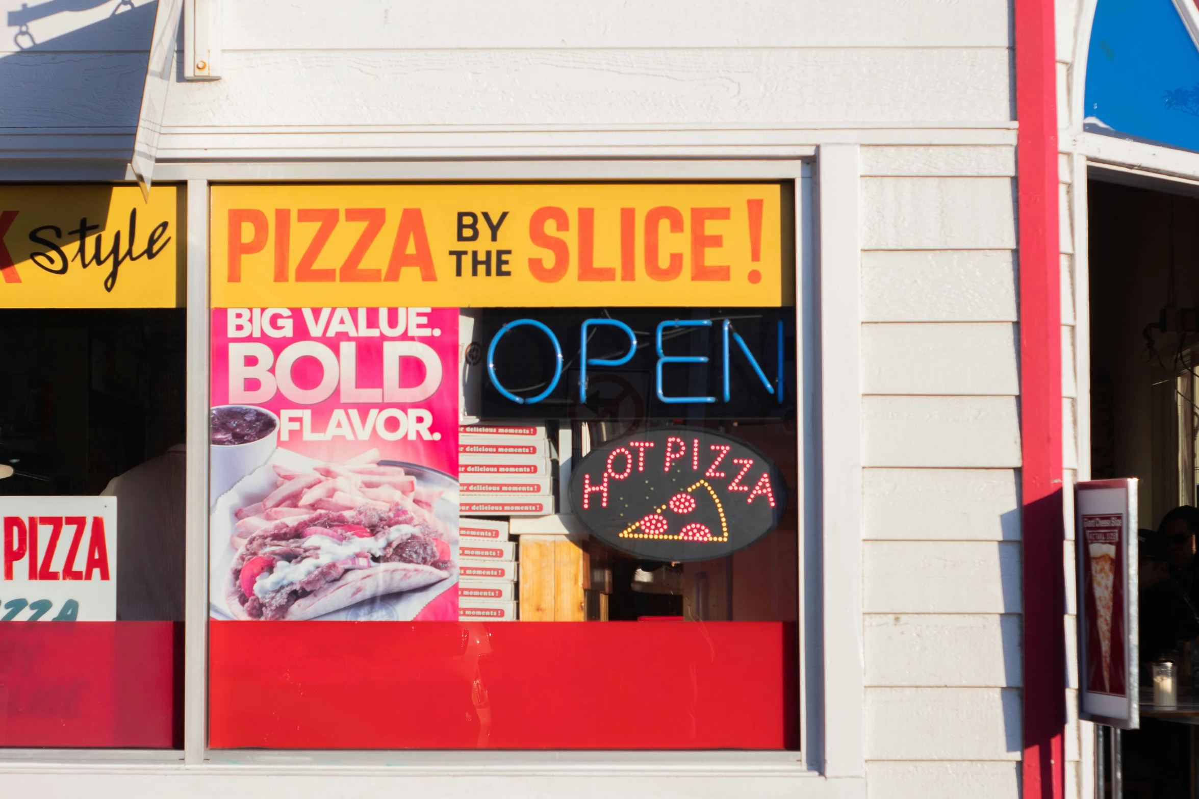 this is a restaurant front window with pizza and a sign