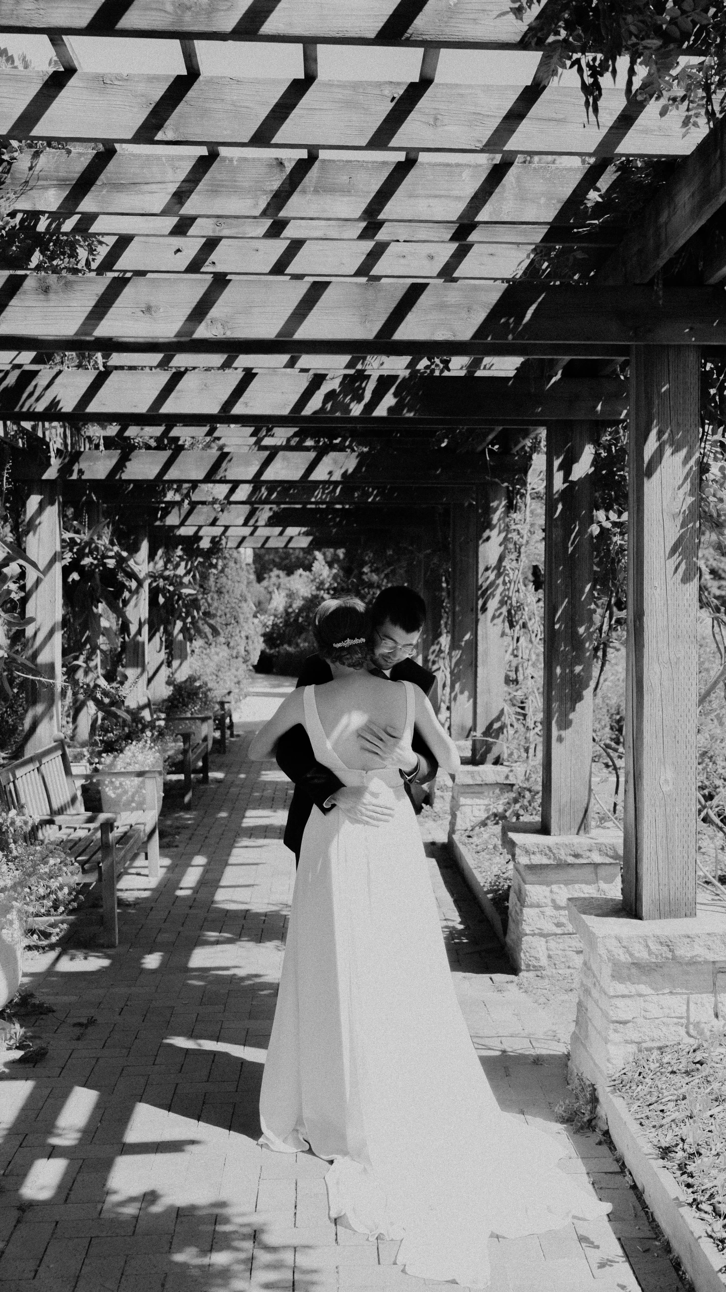 two women in formal wear walk under a pergolan