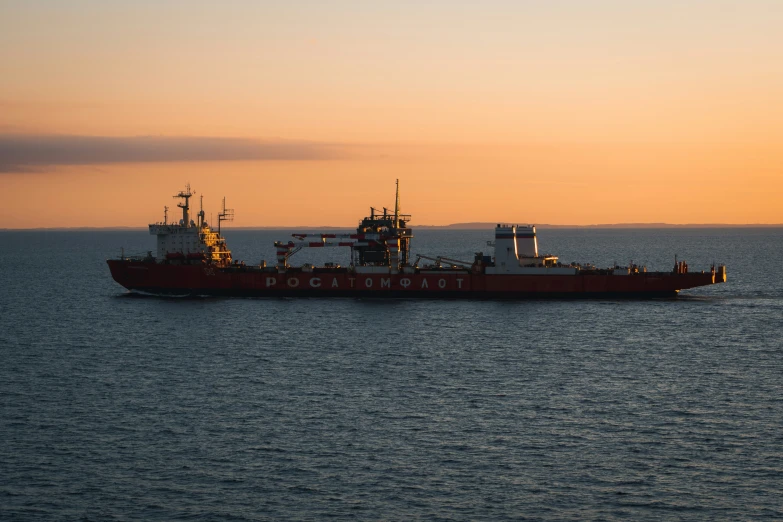 a red boat traveling across the ocean at sunset