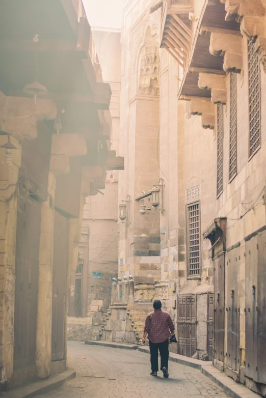 man walking in alley between old stone buildings